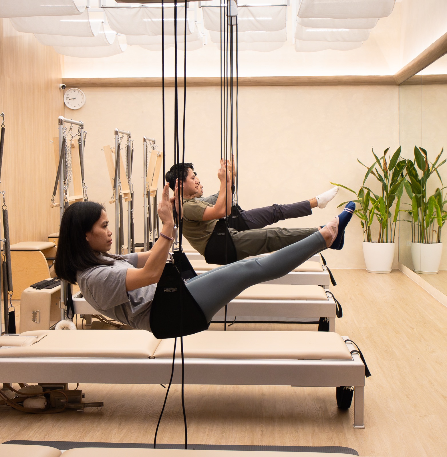 Clients on the reformers in the warm, mirrored studio room